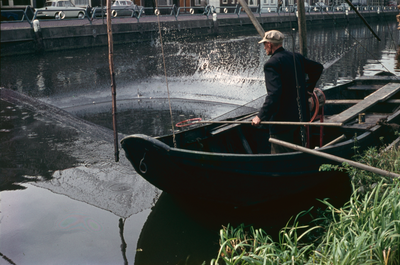849775 Afbeelding van een visser in zijn vissersboot in de Leidsche Rijn te Utrecht, ter hoogte van houthandel De Wit.